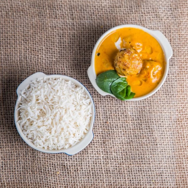 Indian curry with a kofta ball and spinach, served with a side of white rice.